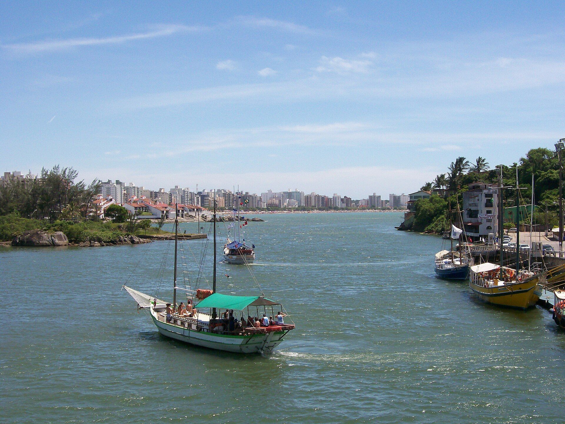 Orla costeira de Guarapari com mar azul, faixa de areia e urbanização à beira-mar.